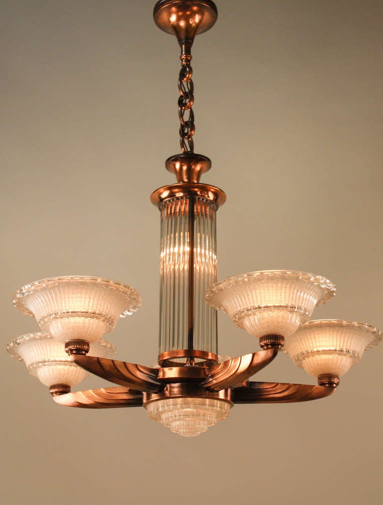Designed by the world renowned Lyon-based firm Atelier Petitot, this simple yet elegant Art Deco chandelier is truly fantastic. This five arm fixture is made of elegant bronze, and features seven lights, including one in the center column, which