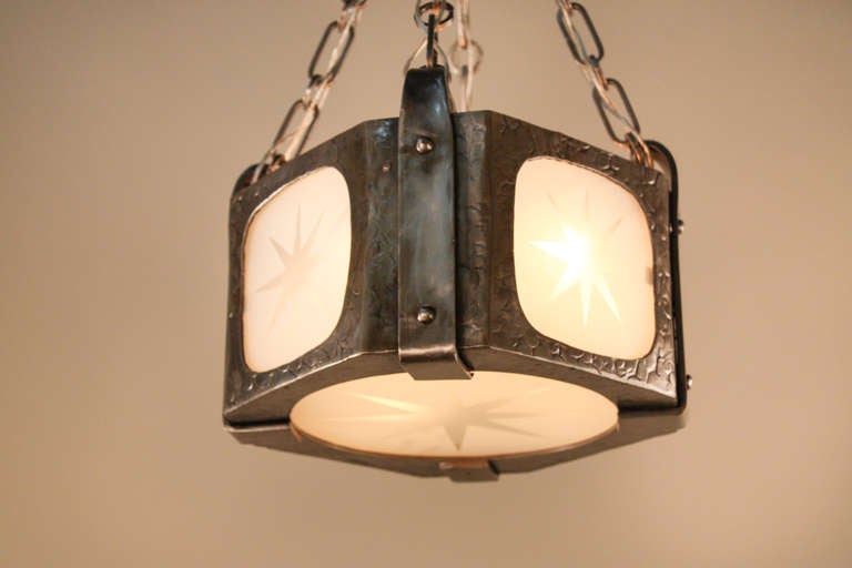 Made in France during the 1930's, this fantastic hanging fixture features a beautiful hand hammered iron body. Four lights brilliantly illuminate the five glass panels, each with an etched starburst design.