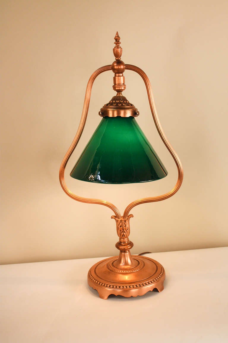 Crafted in the 1930's, this beautiful American Desk lamp features a copper finish over brass design with fabulous detail work. The classic cast green glass shade is easily adjustable with just a touch of a finger (Please see image 5 for more detail).