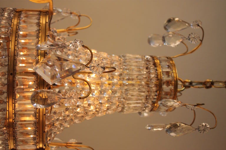 PETITE FRENCH CRYSTAL AND DORE BRONZE CHANDELIER WITH THREE ARMS AND TOTAL OF EIGHT LIGHTS .