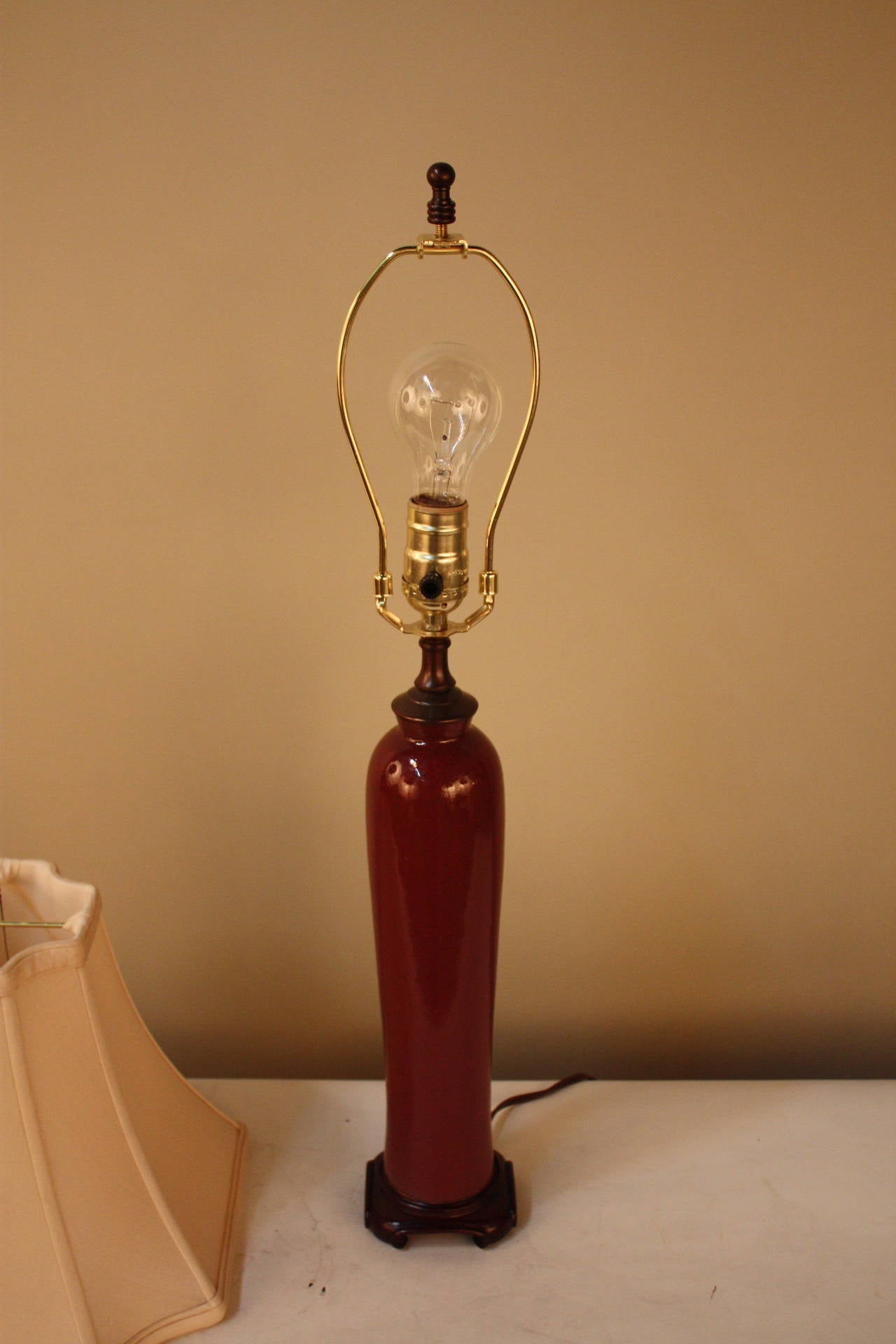 Fantastic Chinese oxblood color pottery table lamp with wooden base and silk lampshade.