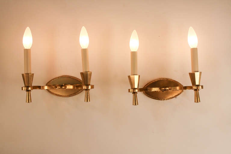 A fabulous pair of double light wall sconces with a simple but elegant bronze design characteristic of traditional European craftsmanship.