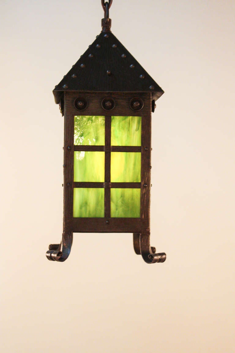 Made of hand hammered iron, this beautiful American Arts & Crafts lantern features four green stained glass panels that elegantly shine with vibrant yet subtle hues.