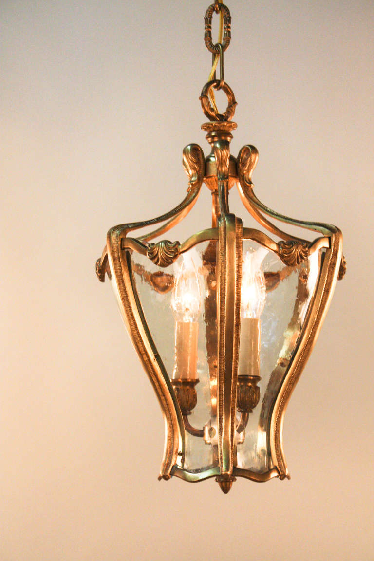 This elegant Spanish lantern is made of bronze and glass. The bronze work has a delicate linear pattern running along the curve of the lantern, adding a simply beautiful detail. The glass panes are made of thick glass with slight wave and bubble to