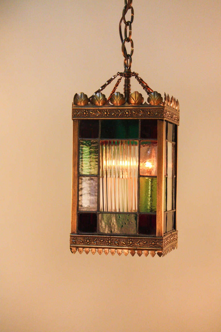 Featuring gorgeous examples of multicolored stained glass, this lantern is a beautiful 19 century four light piece. The bronze rim showcases delicate floral bronze work.