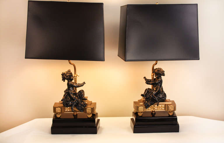 An extraordinary pair of French 19th century bronze chenets, professionally mounted as lamps. The lamps depict a young boy and a girl, sitting on a decorated bronze base with lovely floral detail work. 

Each piece measures 9