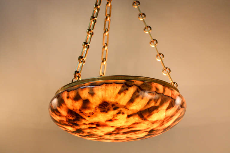 This French 1930s, nine-light chandelier is made of onyx with a beautiful pattern. Stunning in a variety of warm tones, this onyx piece is a gorgeous addition to any room. The onyx is complemented by an elegant bronze chain and canopy. It is 30