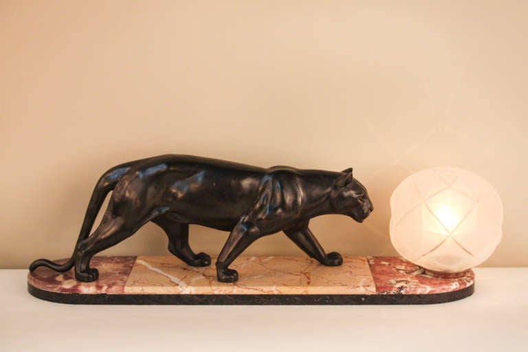 This French Art Deco lamp features a statue of a cat looking curiously towards the light. The clean marble base is bookended by color for a unique look.