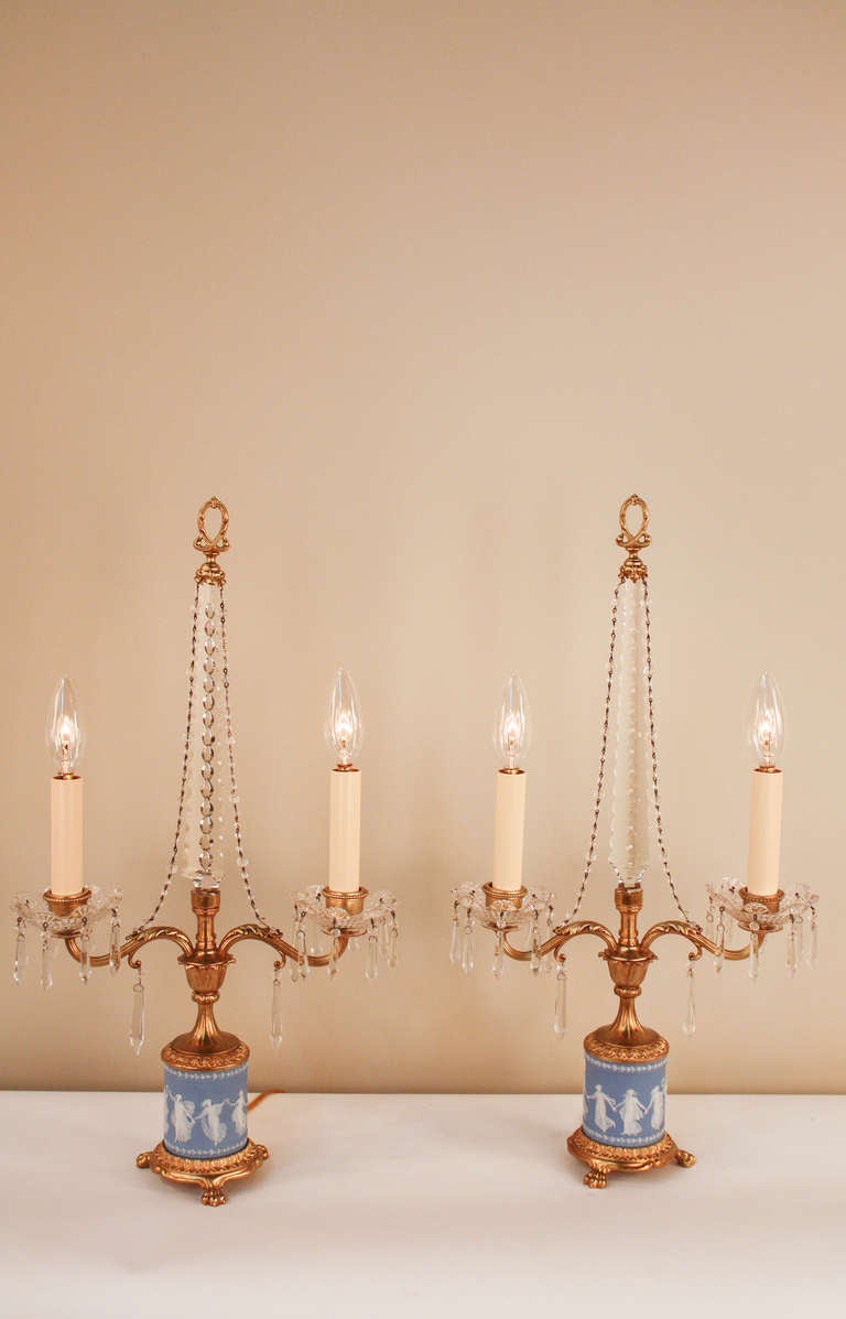 An absolutely stunning pair of elegant table lamps. Made of crystal and bronze, the candelabras feature a stunning bisque wedgwood design, which delicately depicts the mythological dancing graces, exemplary of classic and refined English
