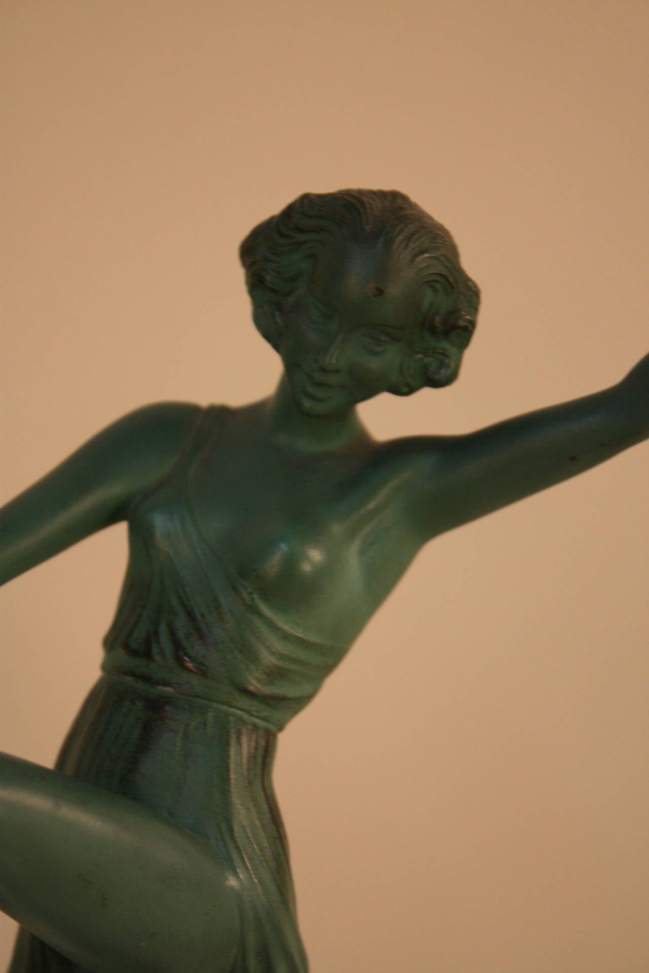 She is a cymbal dancer in Grecian dress. This semi-naked woman with a green patinated finish, mounted on a square stepped black stand and produced by the Le Verrier foundry.