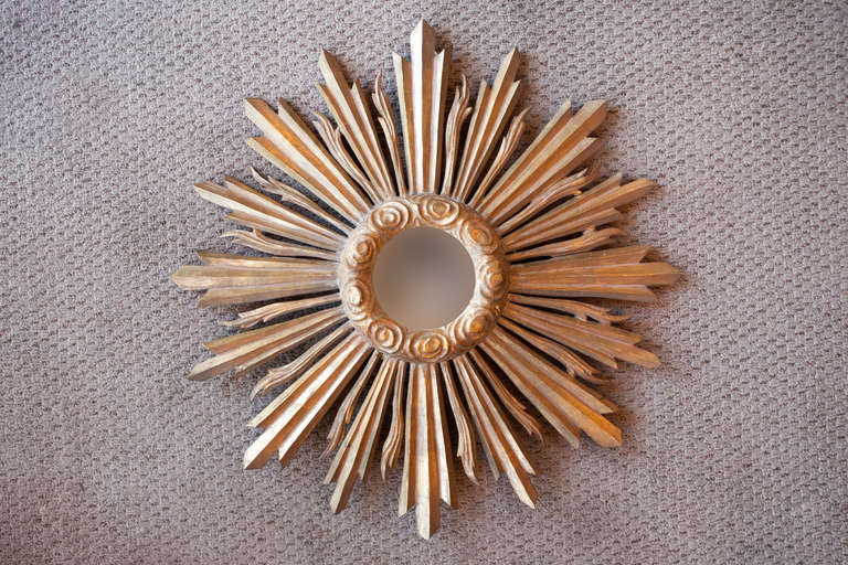 This lovely Spanish mirror is made of gold leaf over wood and glass. The gold leaf highlights the mirror's incredible starburst design of the mirror frame. 

Accented with a center spiral design, this mirror has a bright and lively feel.