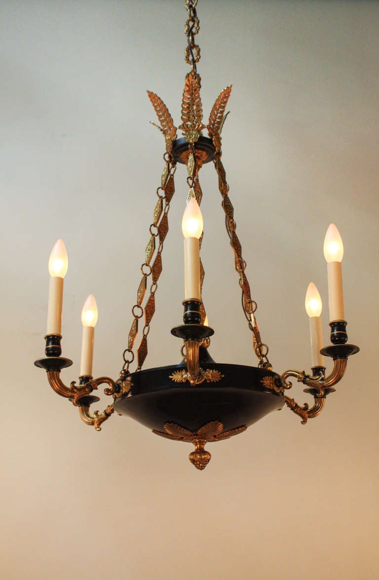This beautiful French Empire Chandelier was made circa 1930, and features six lights. It is made of bronze and black lacquer, with ornate detail work, making it  a classic example of the empire style.