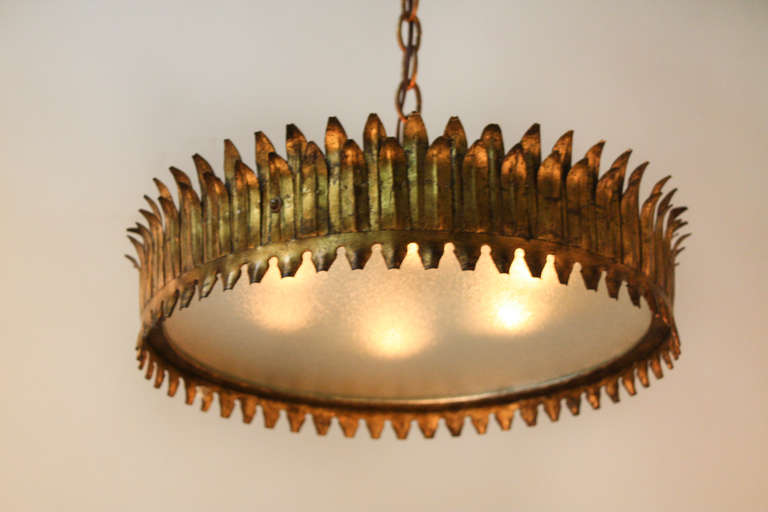 A fantastic flush mount ceiling light. A Midcentury piece made in Spain, this fixture has retained its original gold leaf over iron finish. Six lights sit encased in the beautiful flat fogged glass. This flush mount light measures 9.5