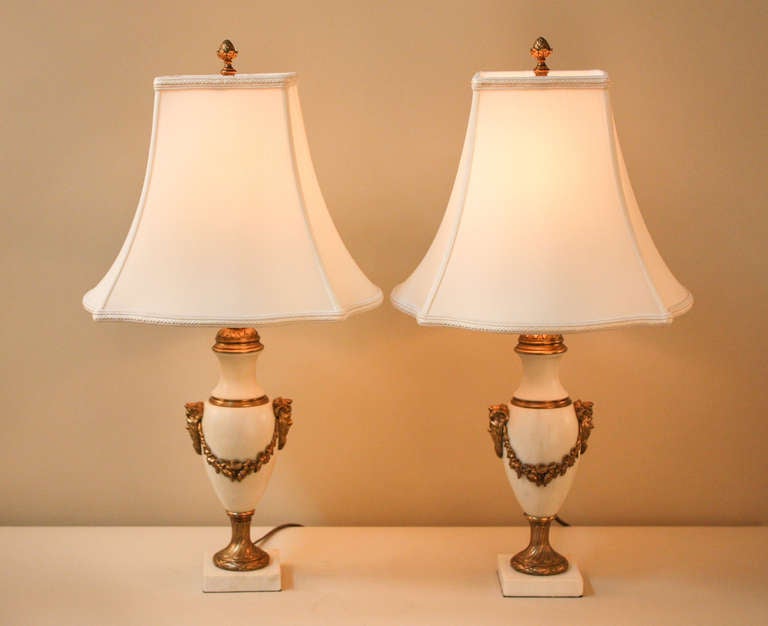 Made in France during the 1930s, this elegant pair of white marble table lamps is adorned with detailed bronze decoration depicting the ancient Greek god Dionysus.<br />
<br />
Each table lamp measures 22