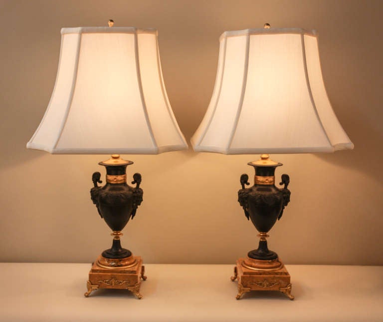 Crafted in France during the 1930's, this each table lamp is mounted on a square marble base. 

A bust of Bacchante, is subtly depicted on either side of the lamp. Bacchante, a priestess of Bacchus, the ancient greek god of wine, is crowned with