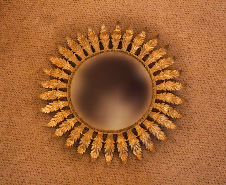 Crafted in Spain during the 1950's, this beautiful sunburst wall mirror features 
a an elegant gold leaf over metal design.

This mirror measures 24