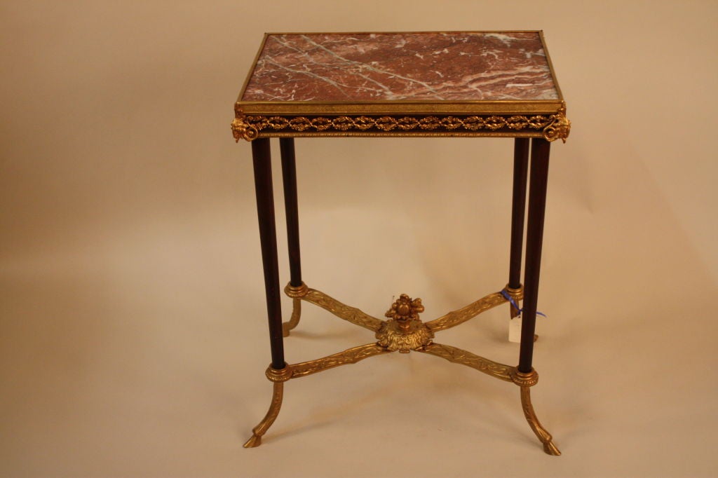 This handsome mahogany table was made in France during the 19th century. A marble top and bronze doré ram's heads in each corner of the table make for a classically elegant look. Finely detailed bronze work throughout this table makes it truly one