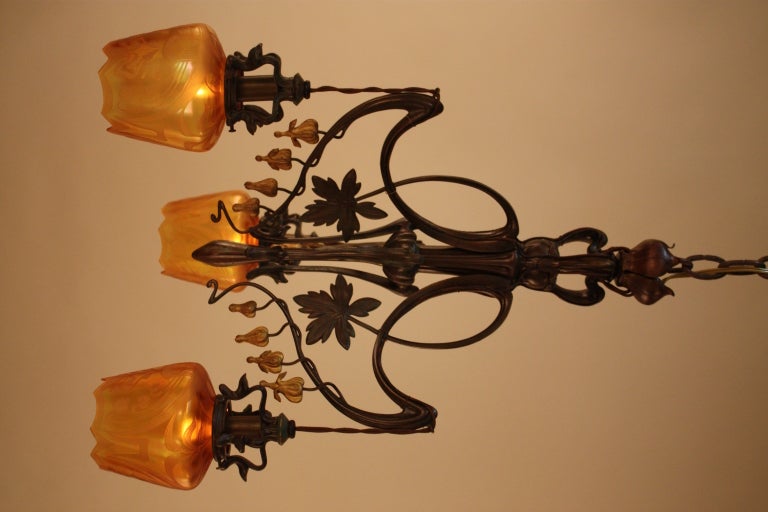 A beautiful etched glass chandelier. Made in the Art Nouveau style, this piece features a gold, green and brown body and fine detail work.