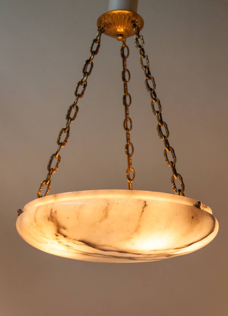 A soft, cream colored alabaster chandelier with black veins hung by three bronze suspending chains. 

This chandelier has six lights and the length of the chains can be adjusted.