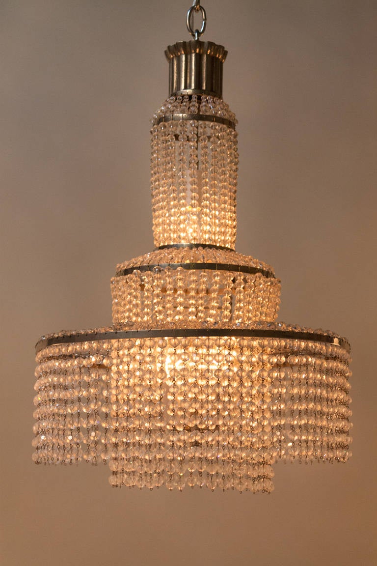 This chandelier was made in France during the second half of the 20th century and could be by famous lighting designer Bagues. This chandelier has been designed in a way that the few hundred small crystal drops make it look like the chandelier is