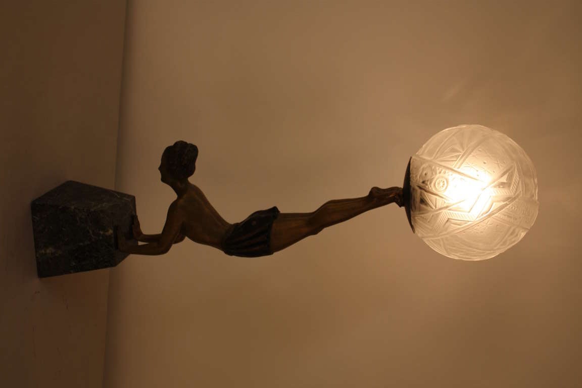A beautiful Art Deco table lamp. Crafted in France during the 1930's, this piece depicts a female acrobat balancing atop a marble base. An elegant, ornately detailed spherical glass shade tops off this great lamp.