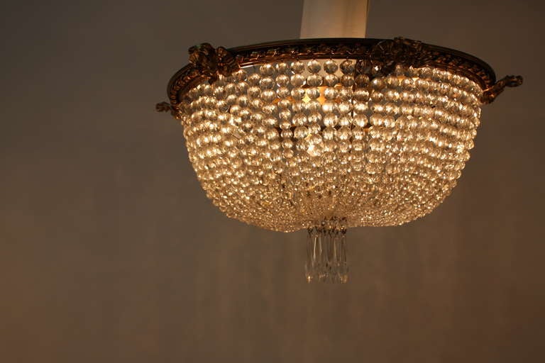 A beautiful four light flush mount fixture. Crafted in France during the 1930's, this elegant chandelier features hundreds of crystals and an ornately detailed bronze rim.