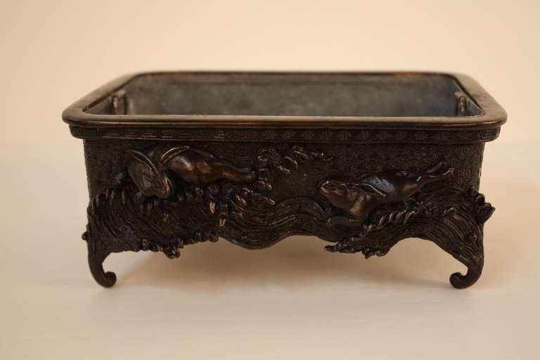 A beautiful bronze jardinere from Japan. On the sides of the piece, an ornate rendering depicts a pair of rabbits chasing each other.