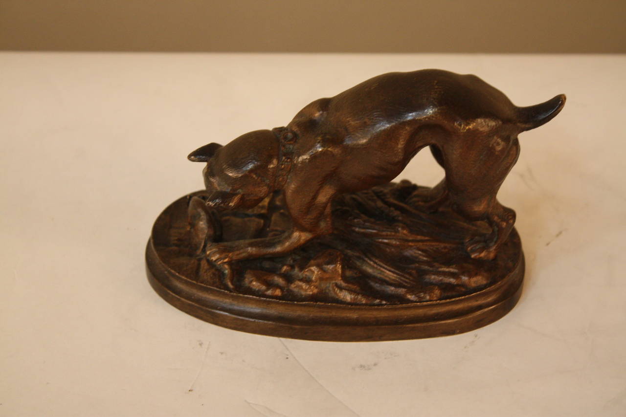 Bronze statue of a boxer dog trapping a mouse on sheaves of wheat.  Adrien Trodoux was a late 19th century French sculptor associated with a group of artists referred to as 'les animaliers.' He was known for depicting animals in naturalistic