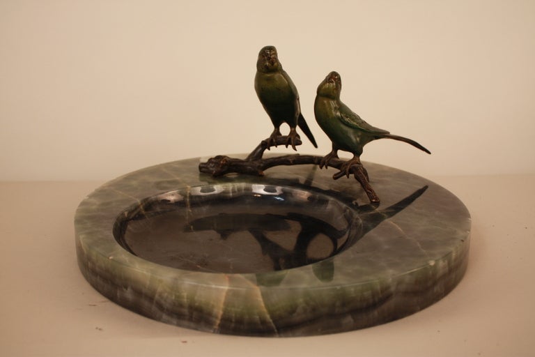 BEAUTIFUL PAIR OF PAINTED BRONZE PARAKEETS SITTING ON A TREE BRANCH OVER A GREEN MARBLE ASHTRAY.