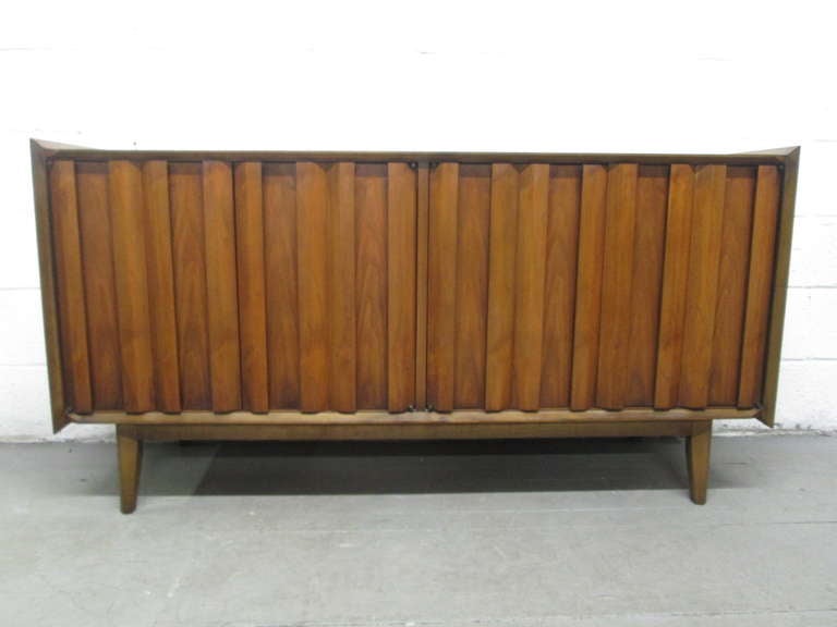 Mid Century Modern Walnut Credenza.  Has a wonderful sculptural front, a shelf inside as well as a single pull out drawer.