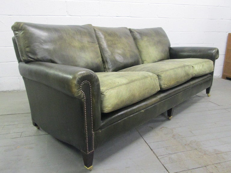 George Smith leather sofa.  Sofa is green leather with distressed and fading areas.  Sofa has down filled seats. Sofa has wheels.  nice look for a mid century modern interior.