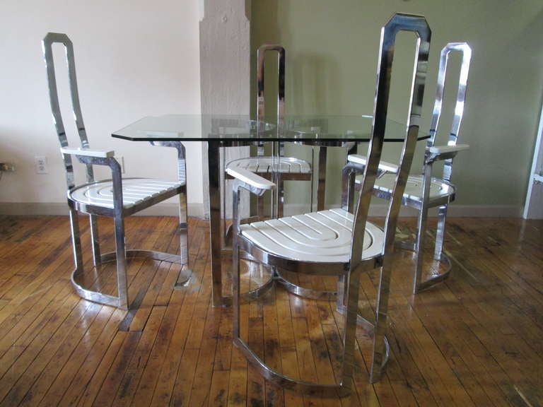 Fabulous designed set of four dining chairs with arms. The heavy chromed frames have lovely soft curves  and white lacquered wood seats and arm rests.  The table has a wonderful designed chrome base with a hexagonal glass shaped top. Some scratches