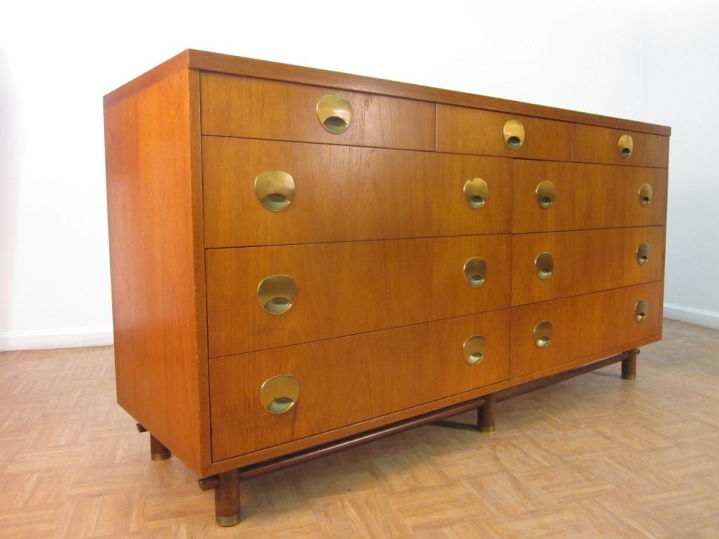 Gorgeous walnut dresser with a total of 9 drawers, brass handles and brass feet. A darker wood to the stretcher. Has a finished back.