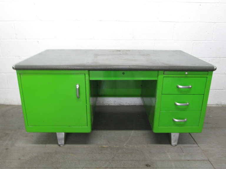 Mid century modern steel desk with a green painted finish.  The desk also has plenty of storage space.  The cabinet to the left of the desk has a tray that comes up and outward. Has a finished back to float in a room.  Measures:  29