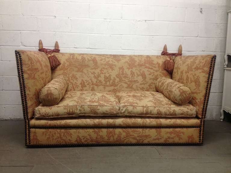 Knole sofa made by the London firm George Smith.  Fully upholstered in original fabric with adjustable sides, two loose seat cushions and two accent pillows.  Both sides of sofa can can come down.  Rope tassels support both upper finials. 
As shown