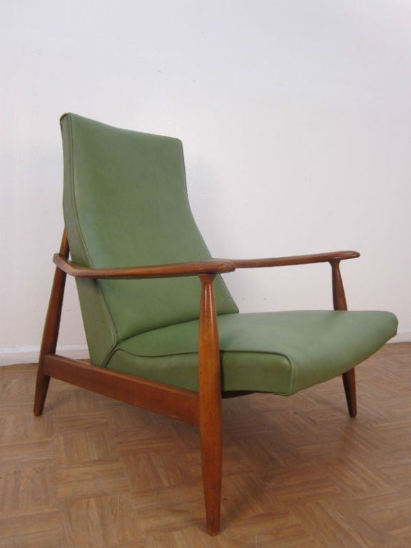 Mid century modern arm chair with a walnut frame and green vinyl upholstery.