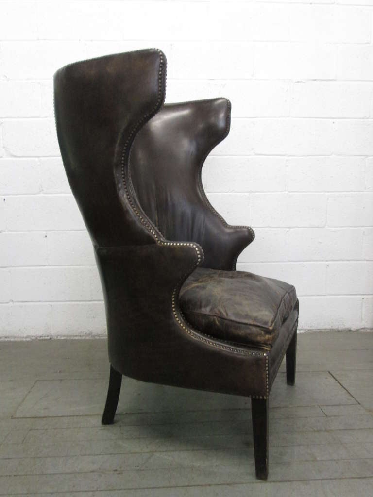 French leather wingback chair with metal stud trim.  Leather is brown has wood legs.  Loose down filled cushioned seat.