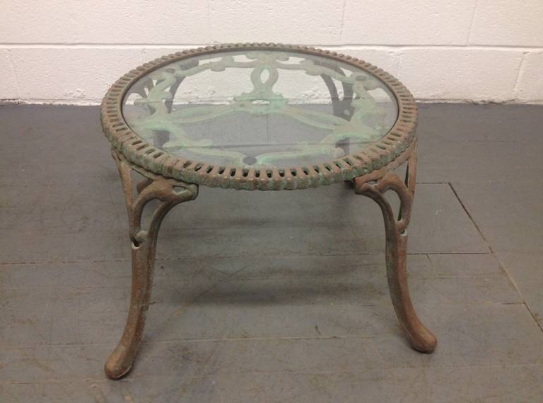 Cast iron garden table. Has a glass top, a painted terracotta finish and the table has green patina. 

There are four matching chairs being sold separately.