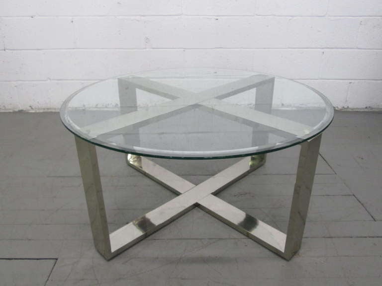 Well designed chrome X base round coffee table with a beveled edge glass top.