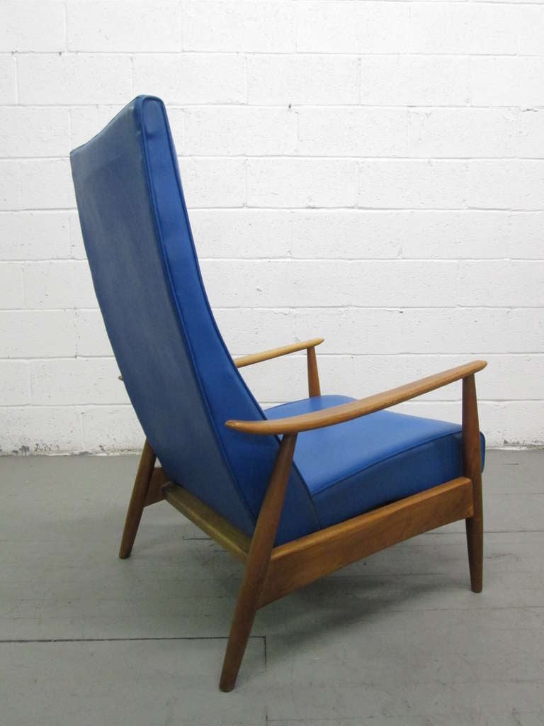 Vintage recliner with a blue and black vinyl designed by Milo Baughman. Sculptural walnut frame. The foot rest extends as the chair reclines back.  Measures in the upright position:  43