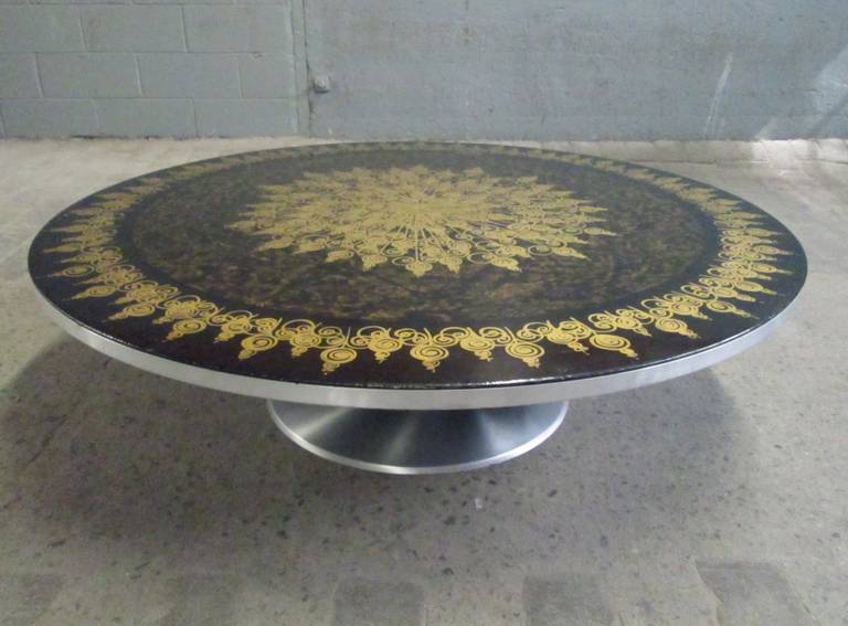 Circular aluminium tulip base coffee table, designed by Poul Cadovius & Bjorn Wiinblad with a hand-painted top decoration by Mygge.
Table produced by Cado, circa 1970s, Denmark. 

Consists of a circular black and brown lacquered top with gold