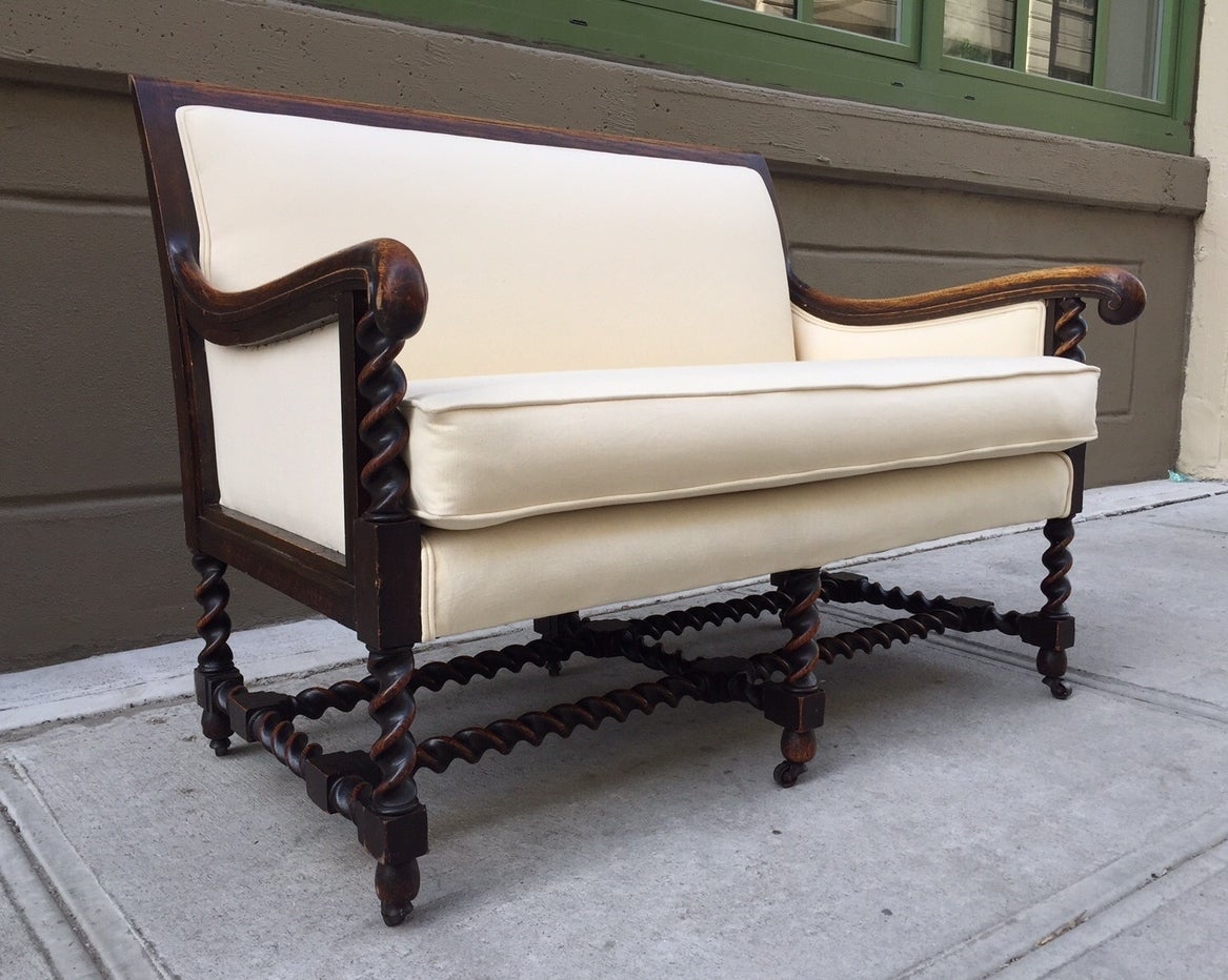 Antique English sofa or loveseat with a barley twist oak frame. Loveseat has wheels, a loose cushioned seat, linen-blend upholstery and great patina.