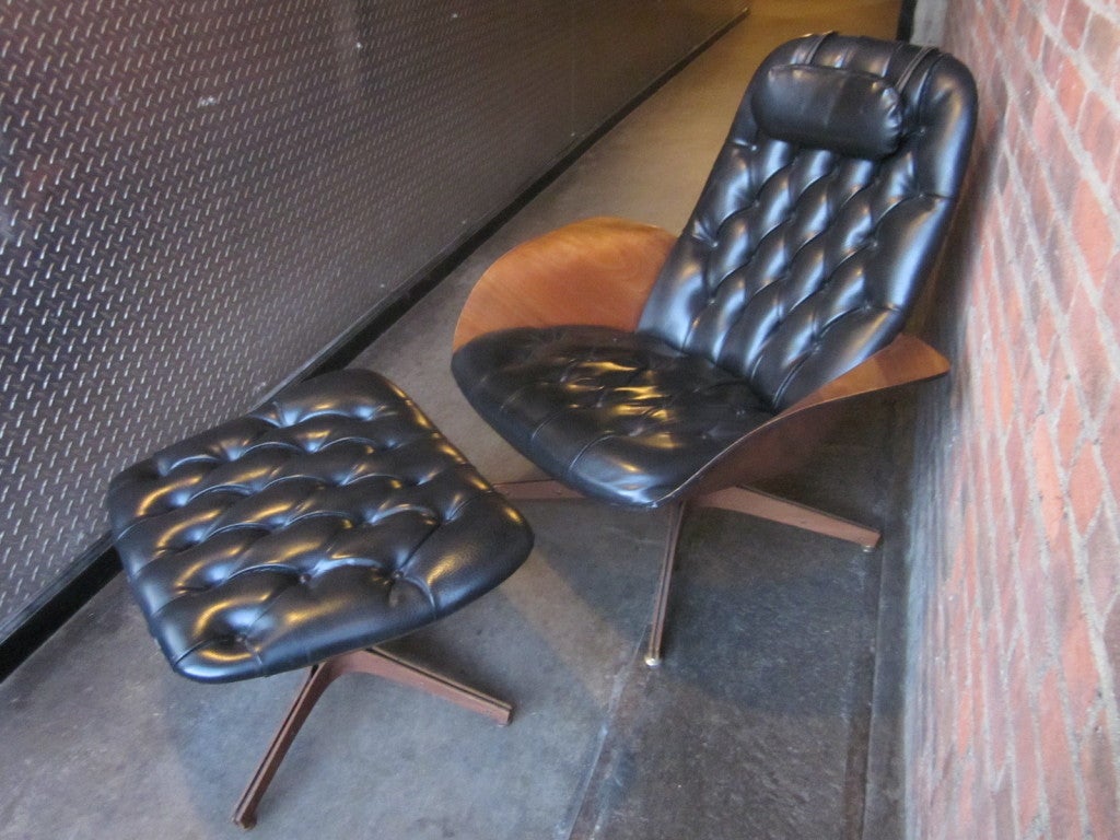 Great looking lounge chair and matching ottoman designed by George Mulhauser for Plycraft. Chair and ottoman is black tufted vinyl.  Both items swivel.  The shell of the chair, winged arms and legs are plywood.