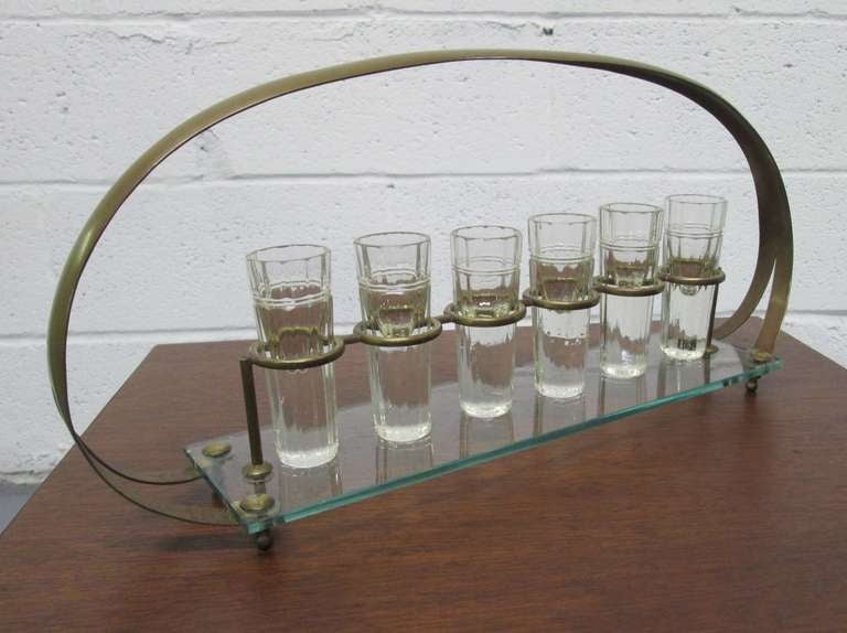 Six Baccarat cut-glass, shot glasses with bronze handle and holders, on a glass tray. 
Caddy measures 8" H x 16.25" W x 3.5" D. Each shot glass measures approximately 3.5" H.
