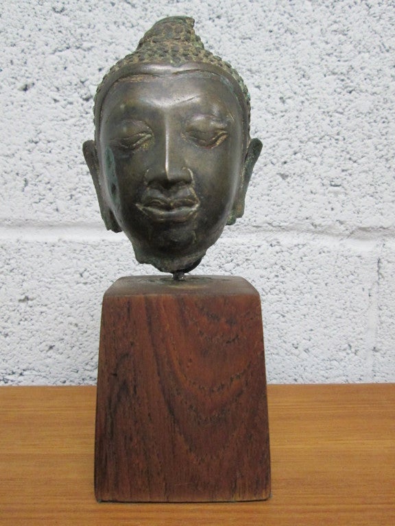 Tête de bouddha unique en bronze sur socle en noyer.