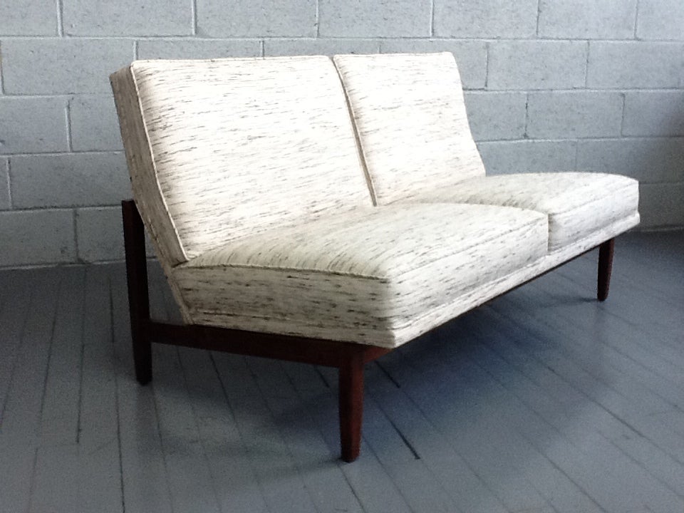 Knoll loveseat with upholstery and a walnut frame.