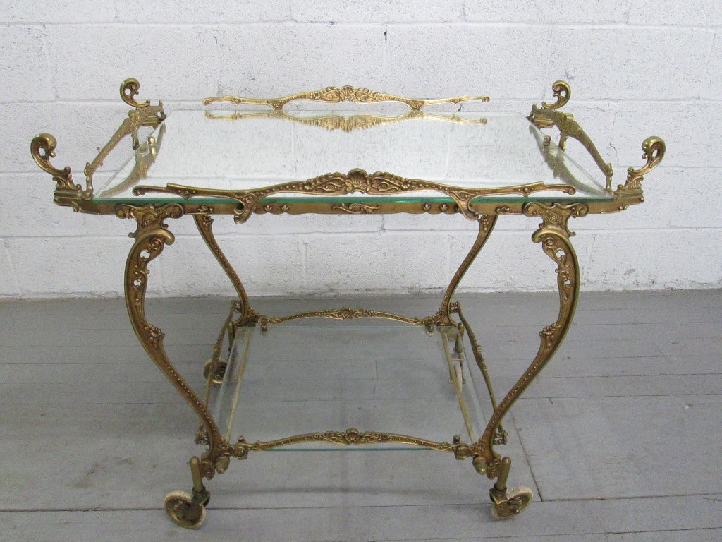 Stunning Baroque style brass tea cart with a mirrored top and glass bottom shelf.