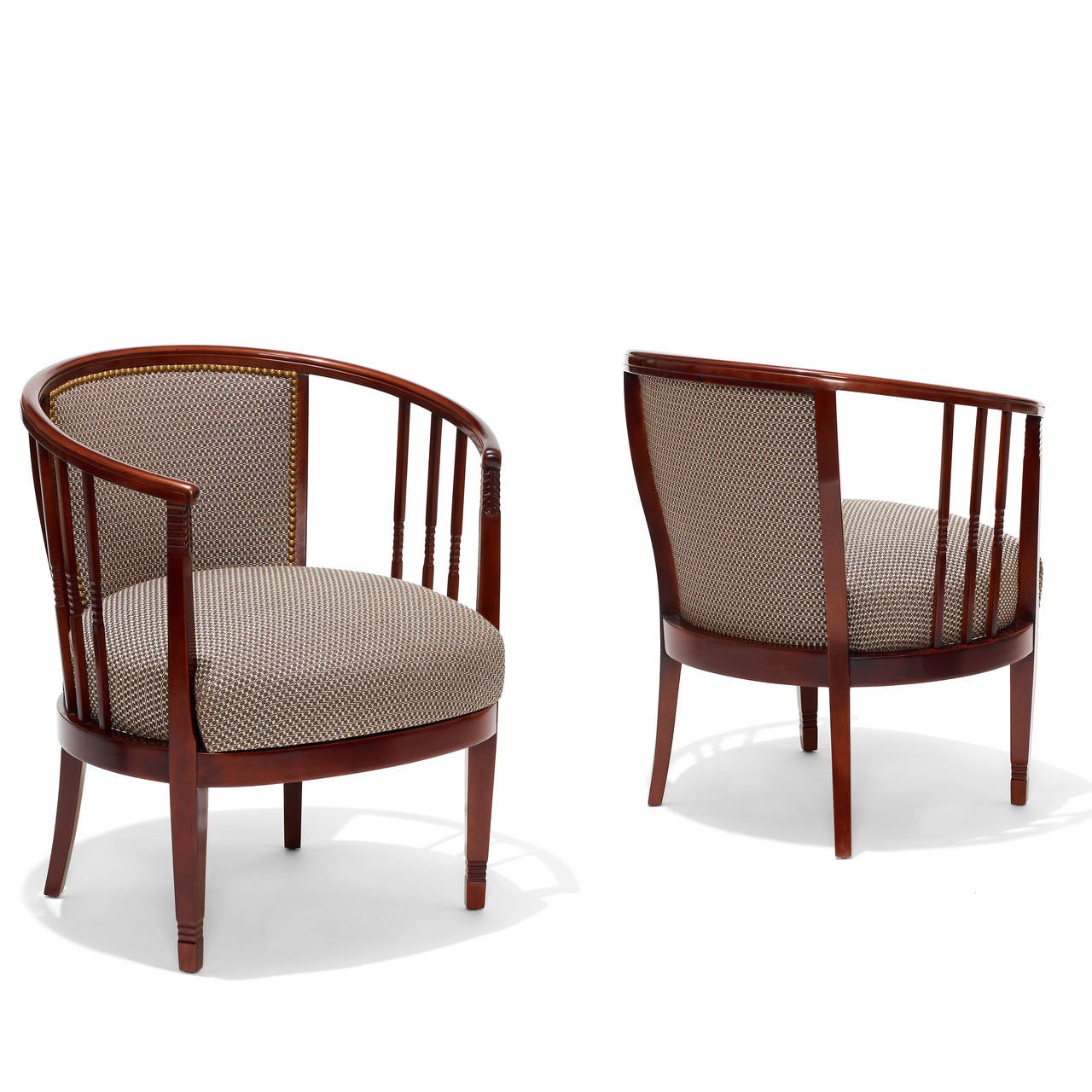 Striking pair of Arts and Crafts armchairs having an oval footprint, with continuous curved top rail angling down slightly from the upholstered back to form two curved arms. The arm supports feature handsome chip carving details. 

Most likely a