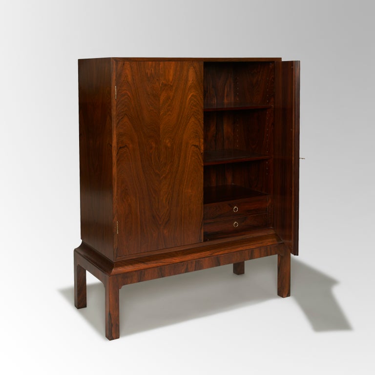 Between 1927 and 1966 the Copenhagen Cabinetmaker’s Guild held annual exhibitions to share new designs and promote excellence in craftsmanship. The meticulous execution of this cabinet on stand speaks to the high standards of Danish cabinet making