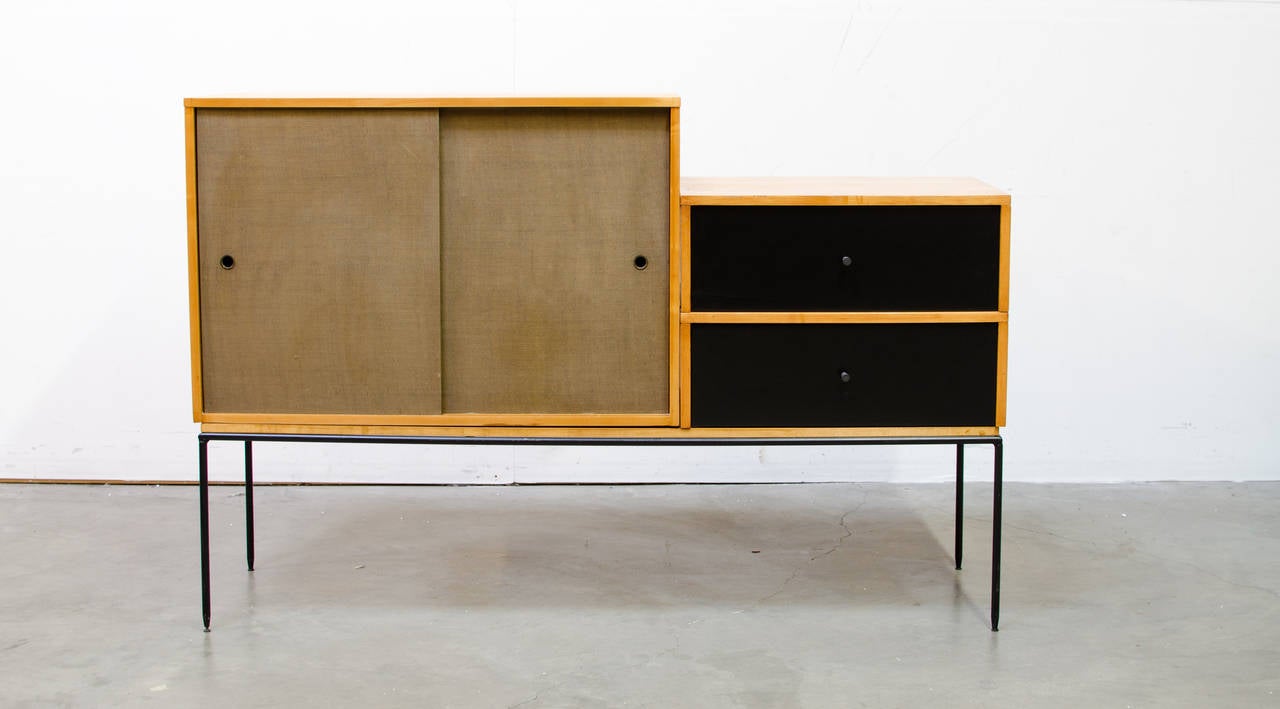 A unique modular cabinet system designed by Paul McCobb featuring a two-door cabinet with a shelf and two single drawers with sculpted brass pulls.